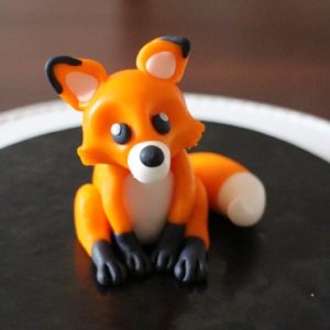 Finished polymer clay fox sitting, made from orange, white and black clay
