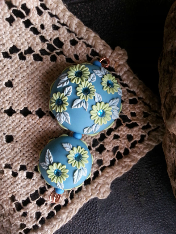 polymer clay floral embroider beads set with backgrounds of aqua, flowers and stitching in lime green and leaves in pale aqua.