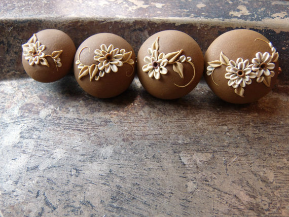 handcrafted 4 embroider beads on a bronze-brown background with flowers in ivory and foliage in light bronze.