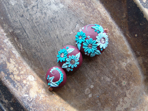 set 3 beads on a cognac hued background and floral in shades of teal.