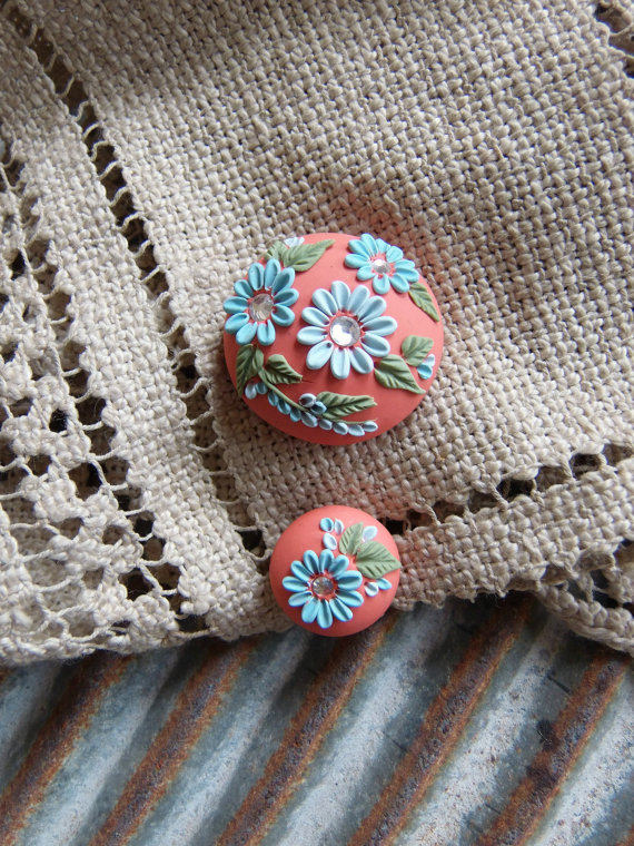 polymer clay floral embroider beads set on an orange background and floral and foliage in shades of baby blues and green.