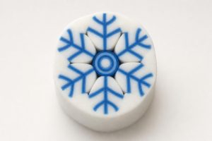 Blue and white polymer clay snowflake cane showing the six-armed snowflake cross-section